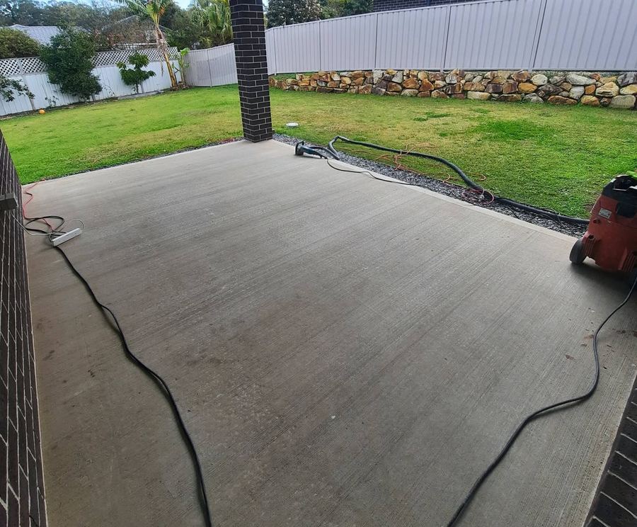 Grinding a concrete driveway on a Floor Candy job, extraction hose running across the slab