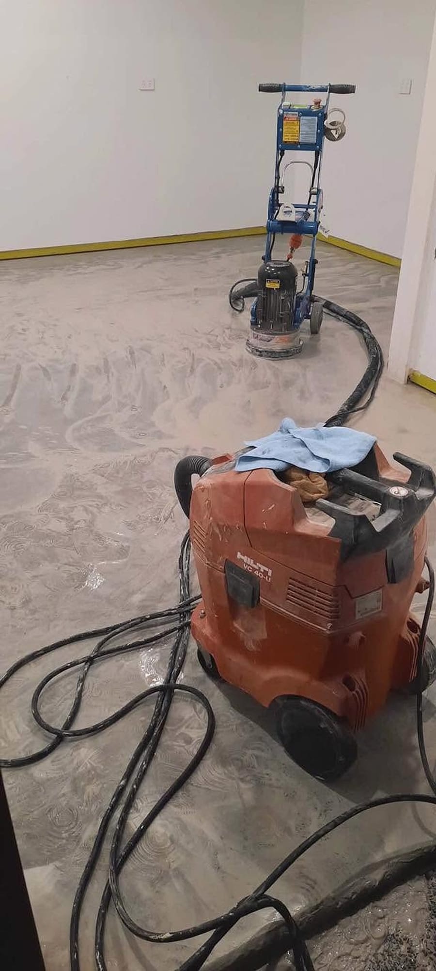 Floor grinder and Hilti industrial dust extractor mid-grind on a Floor Candy job