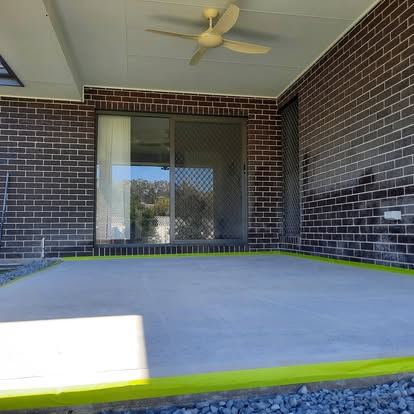 Coated alfresco slab in a slate blue finish beside a brick wall